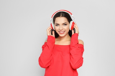 Photo of Young woman listening to Christmas music on color background