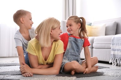 Photo of Happy mother with her children on floor at home