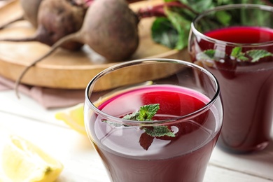 Photo of Glass of beet juice with mint on table, closeup