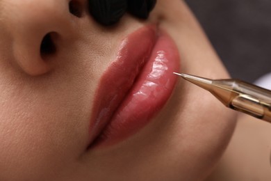 Young woman undergoing procedure of permanent lip makeup in tattoo salon, top view