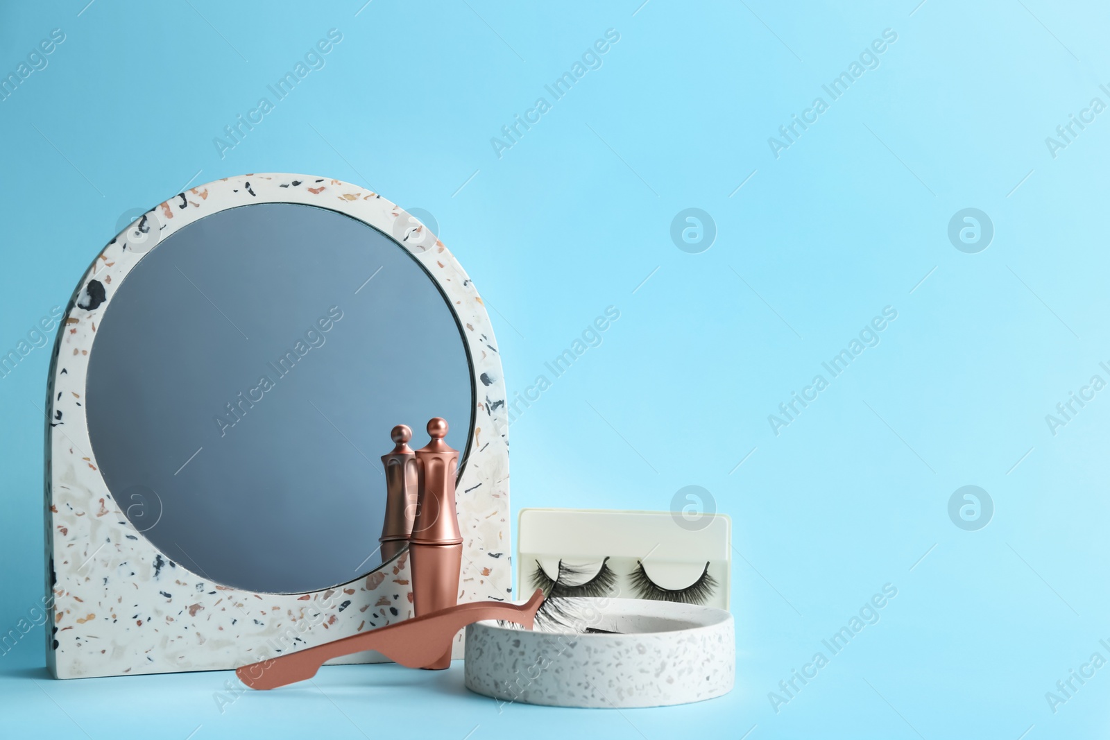 Photo of Magnetic eyelashes and accessories on light blue background. Space for text