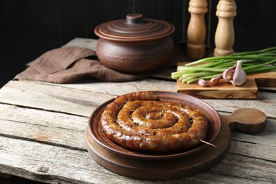 Plate with tasty homemade sausages on wooden table, space for text