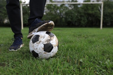 Man with dirty soccer ball on green grass outdoors, closeup. Space for text