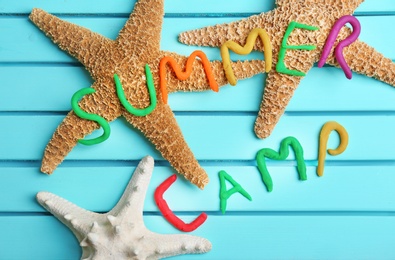 Photo of Flat lay composition with words SUMMER CAMP made from modelling clay and sea stars on color background