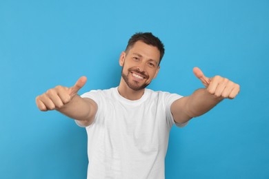 Photo of Man showing thumbs up on light blue background