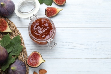 Photo of Delicious fig jam and fresh fruits on white wooden table, flat lay. Space for text