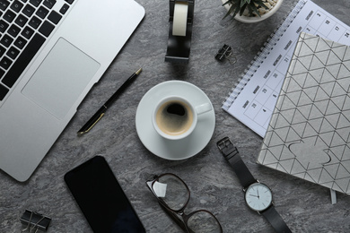 Photo of Flat lay composition with laptop, smartphone and stationery on dark grey table