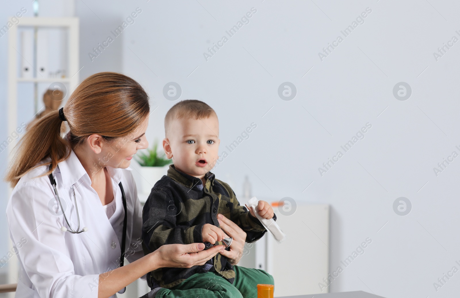 Photo of Children's doctor working with little patient in hospital. Space for text