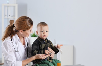 Photo of Children's doctor working with little patient in hospital. Space for text