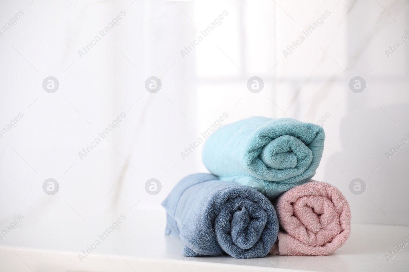 Photo of Rolled fresh towels on countertop in bathroom. Space for text