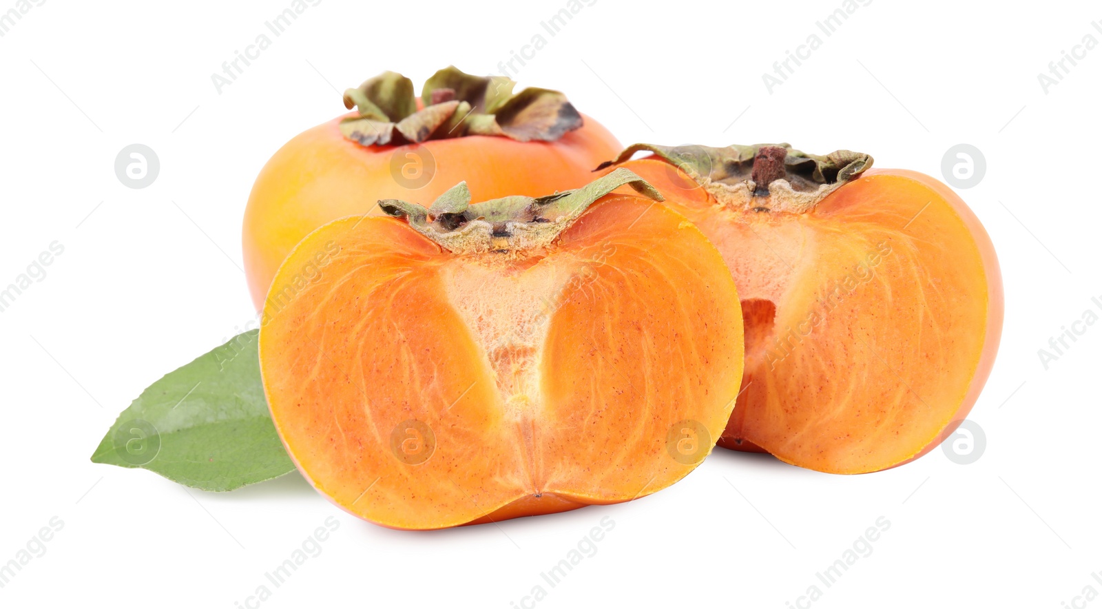 Photo of Whole and cut delicious ripe juicy persimmons with green leaf on white background