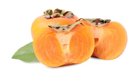 Photo of Whole and cut delicious ripe juicy persimmons with green leaf on white background