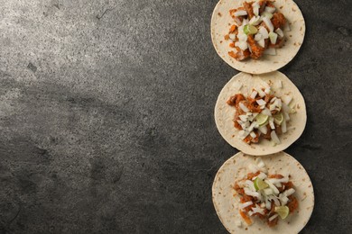 Delicious tacos with vegetables, meat and lime on grey textured table, flat lay. Space for text