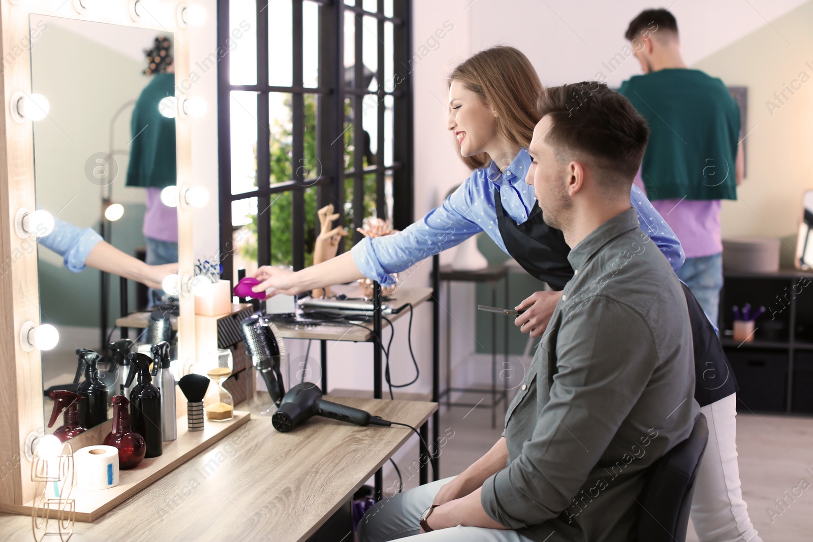 Photo of Professional hairdresser working with client in beauty salon