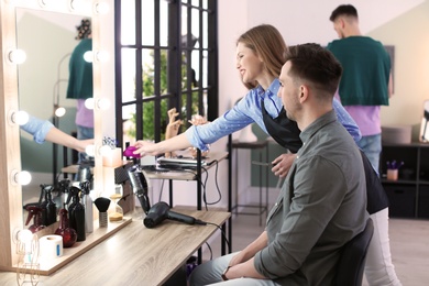 Professional hairdresser working with client in beauty salon