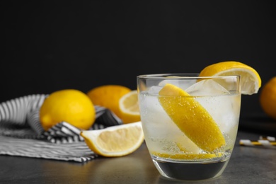 Photo of Soda water with lemon slices and ice cubes on grey table. Space for text