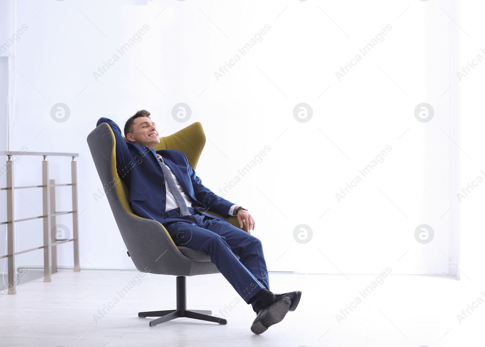 Photo of Young businessman sitting in comfortable armchair indoors. Space for text