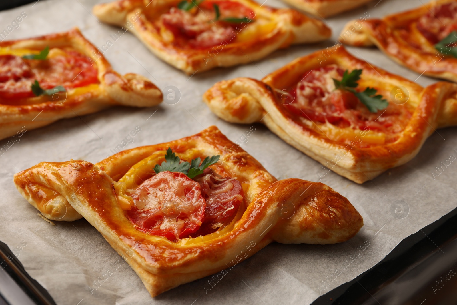 Photo of Fresh delicious puff pastry with tasty filling on baking sheet, closeup