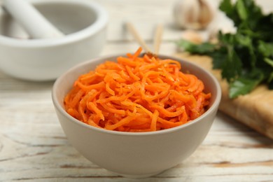 Photo of Delicious Korean carrot salad in bowl on white wooden table