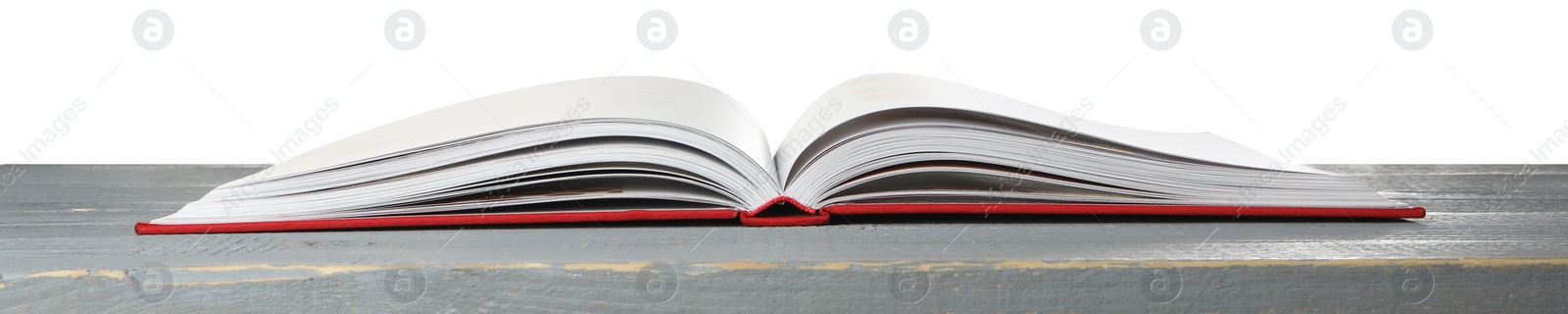 Photo of Open book with red cover on wooden table against white background