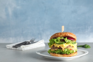 Photo of Plate with tasty burger on table against color background. Space for text