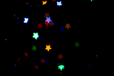 Photo of Blurred view of colorful star shaped lights on black background. Bokeh effect