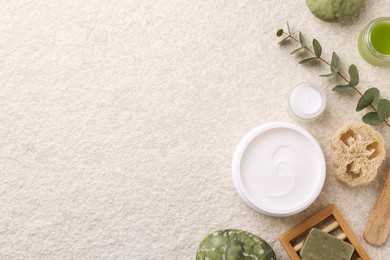 Photo of Flat lay composition with moisturizing cream in open jars and other body care products on light textured table. Space for text