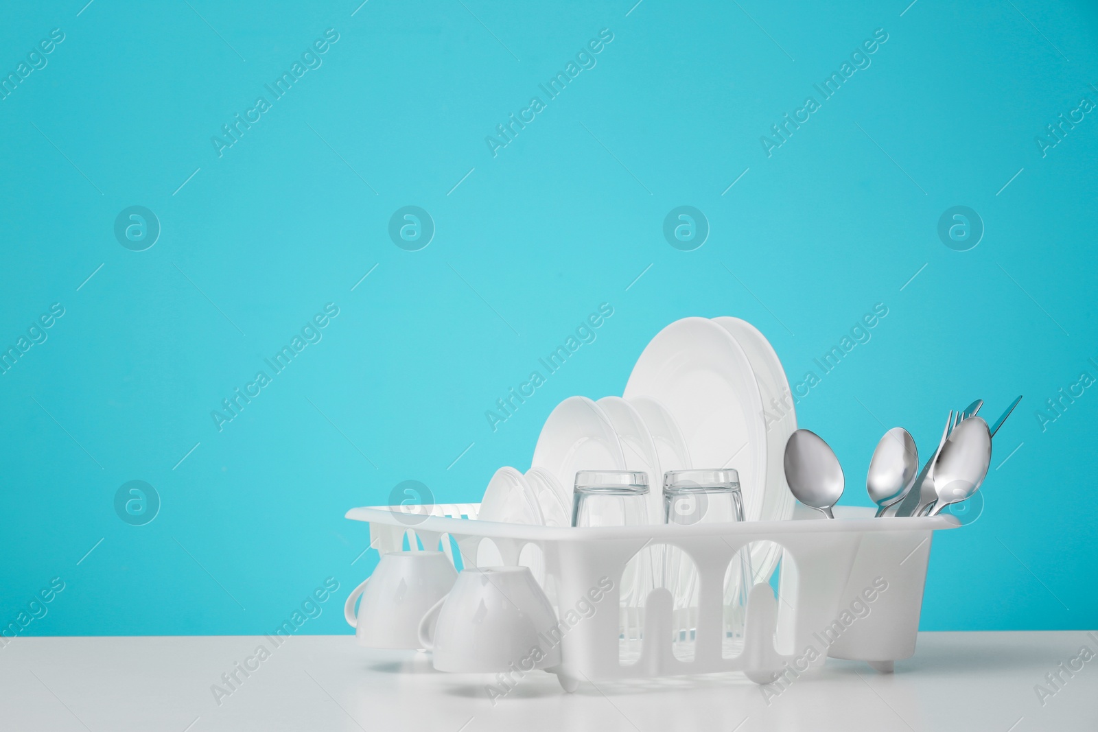 Photo of Set of clean dishware on table against color background. Space for text