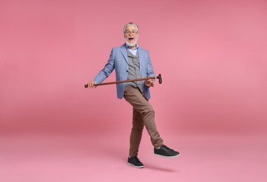 Photo of Emotional senior man with walking cane on pink background
