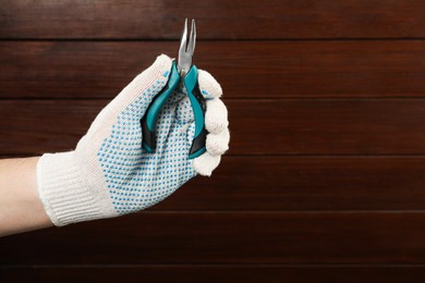 Man with bent nose pliers on wooden background, closeup. Space for text