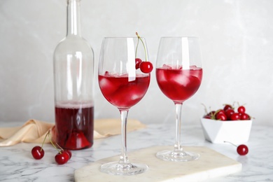 Photo of Delicious cherry wine with ripe juicy berries on white marble table