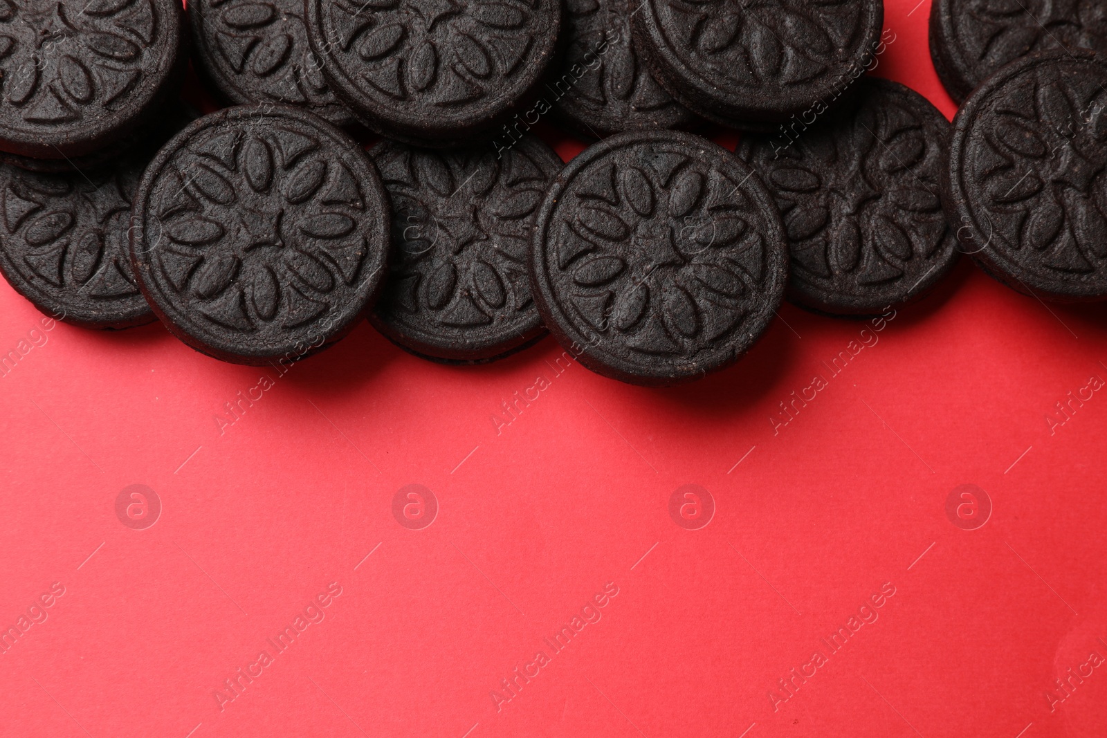 Photo of Tasty sweet sandwich cookies on red background, flat lay. Space for text