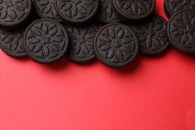 Photo of Tasty sweet sandwich cookies on red background, flat lay. Space for text