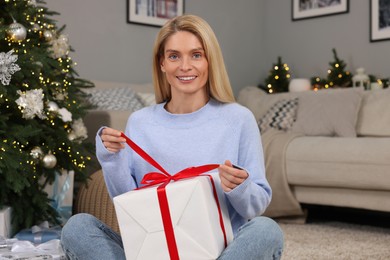 Photo of Happy woman opening Christmas gift at home