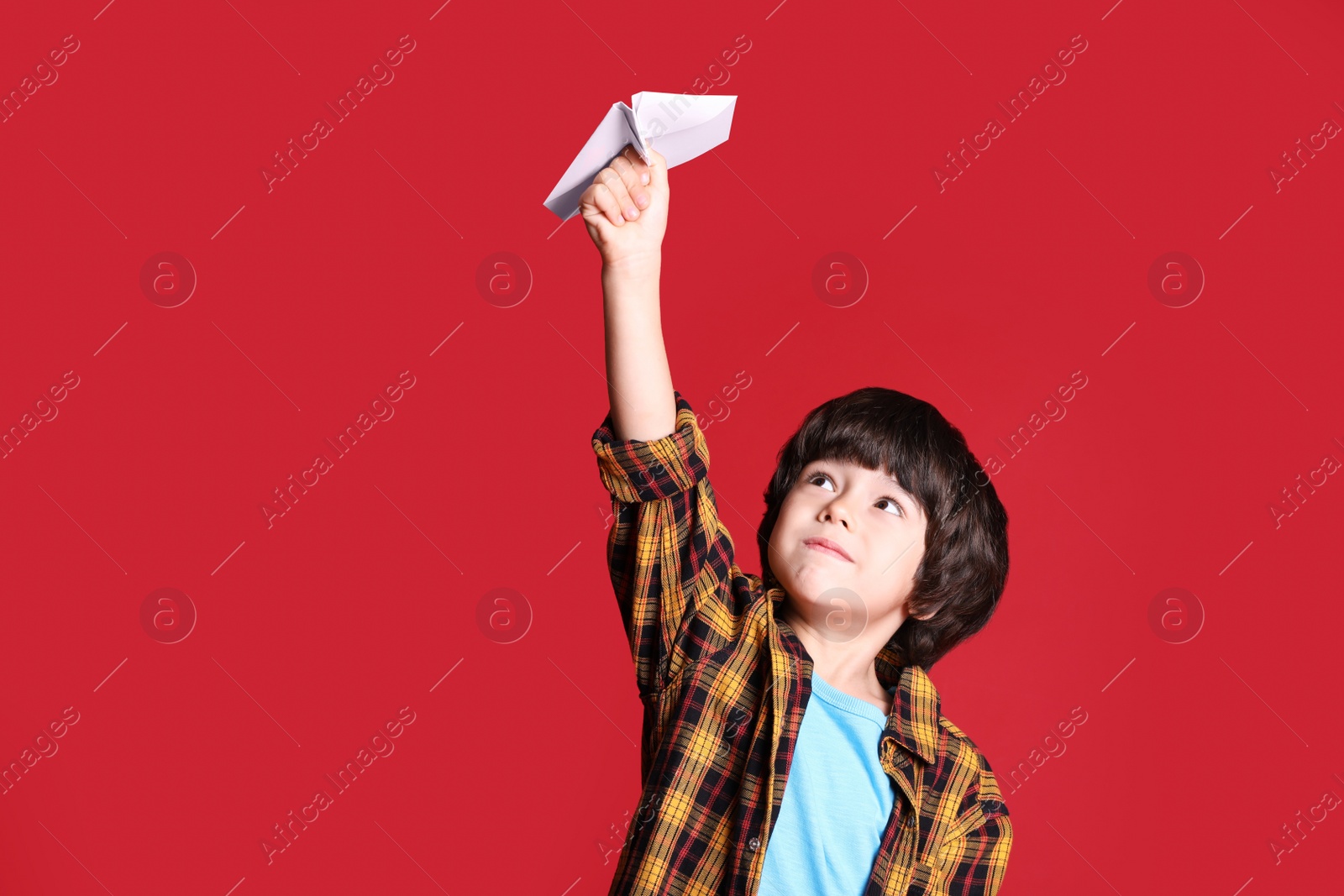 Photo of Cute little boy with paper plane on red background