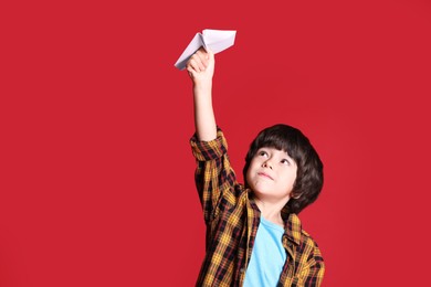 Photo of Cute little boy with paper plane on red background