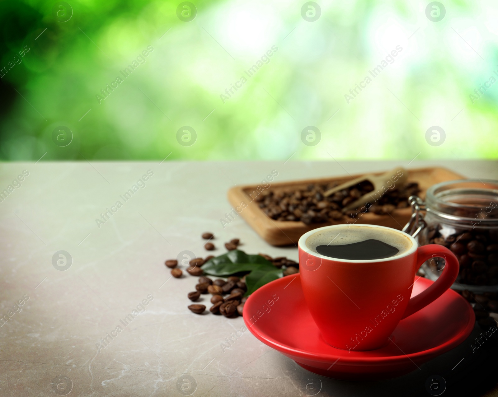 Image of Cup of aromatic hot coffee and beans on marble table outdoors. Space for text