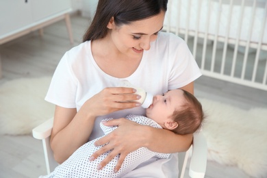 Photo of Woman feeding her baby from bottle at home