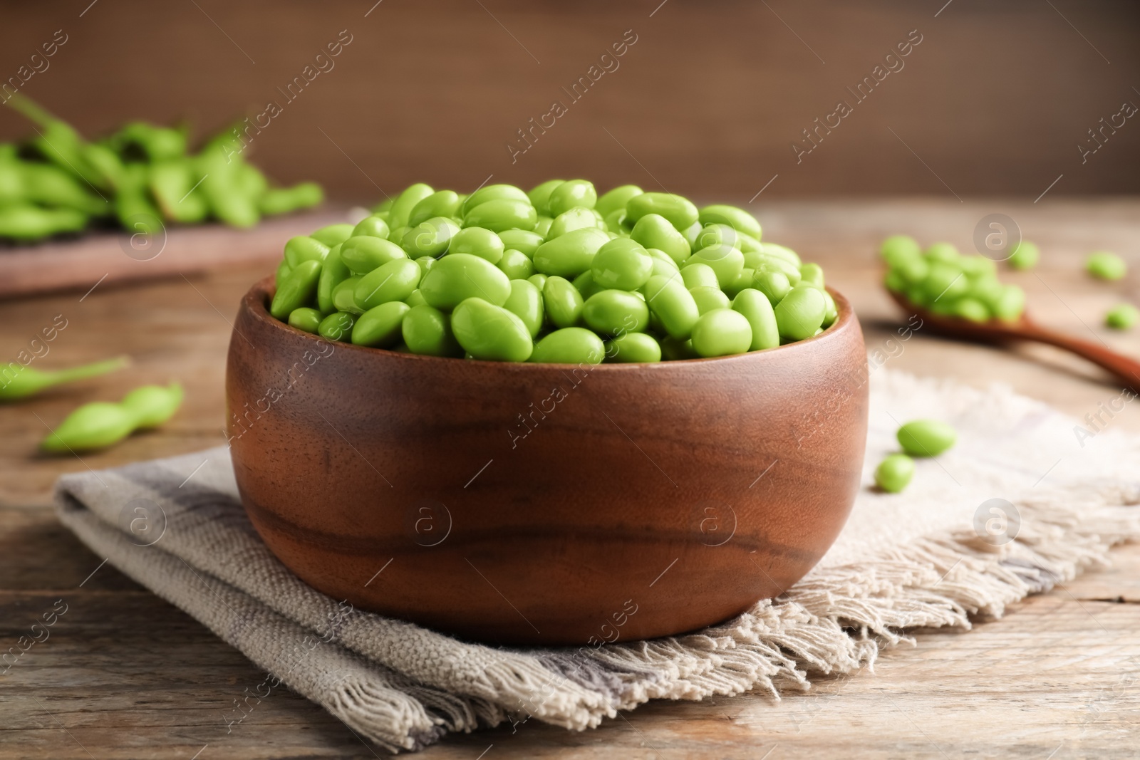 Photo of Bowl of delicious edamame beans on wooden table, closeup