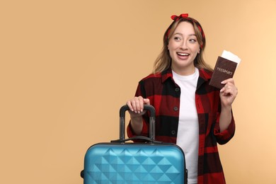 Happy young woman with passport, ticket and suitcase on beige background, space for text