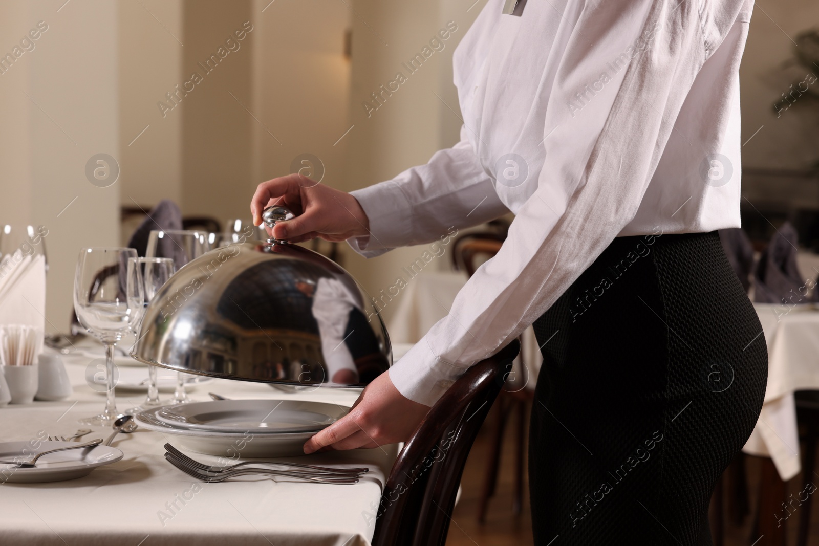 Photo of Woman setting table in restaurant, closeup. Professional butler courses