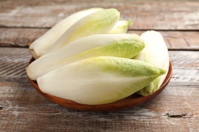 Photo of Fresh raw Belgian endives (chicory) on wooden table
