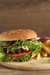 Delicious burger with beef patty and french fries on wooden table, closeup