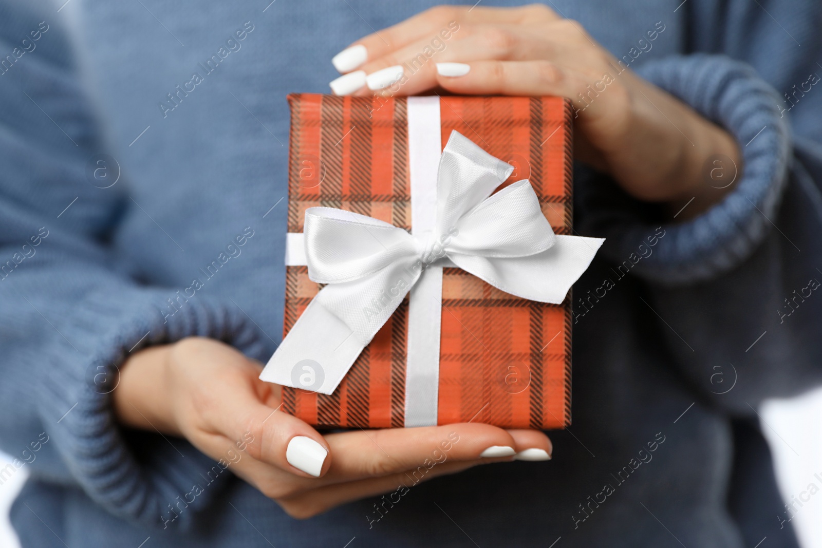 Photo of Woman in warm sweater holding Christmas gift, closeup view