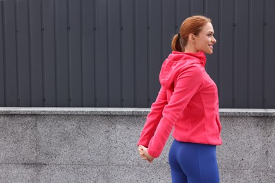 Photo of Beautiful woman in gym clothes doing exercises on street, space for text