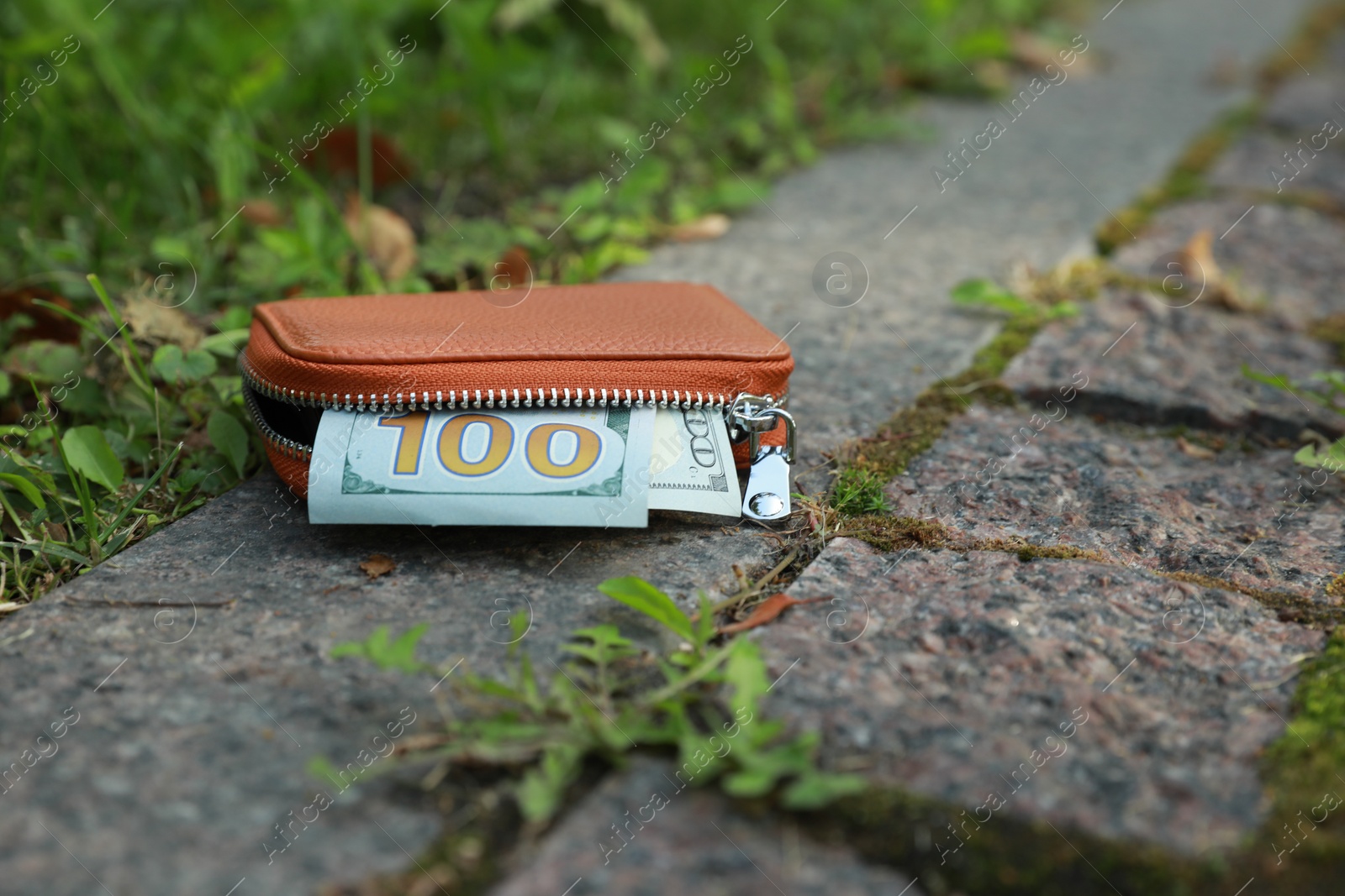 Photo of Brown leather purse on pavement outdoors, closeup. Lost and found