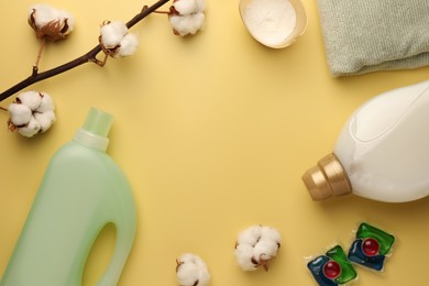 Photo of Flat lay composition with bottles of fabric softener on pale yellow background. Space for text