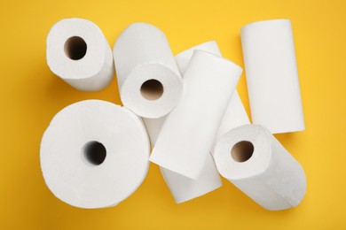 Photo of Many rolls of paper towels on yellow background, flat lay