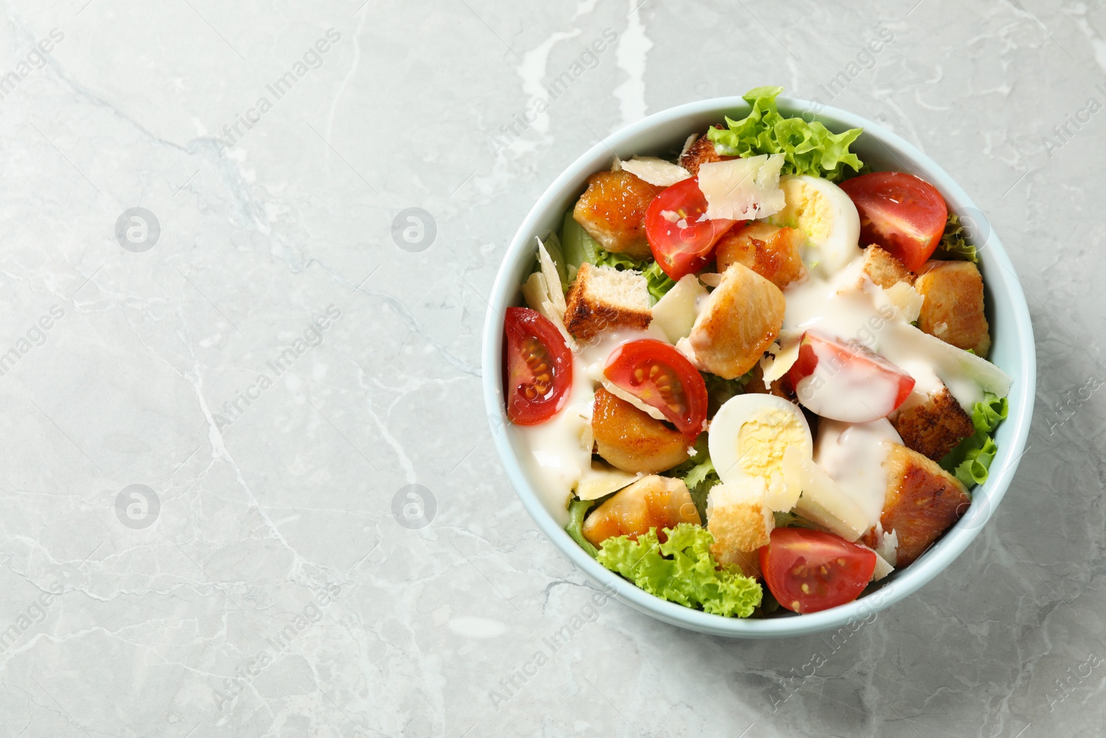 Photo of Delicious fresh Caesar salad on grey marble table, top view. Space for text