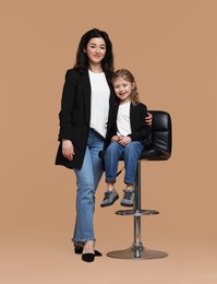Beautiful mother with little daughter on beige background
